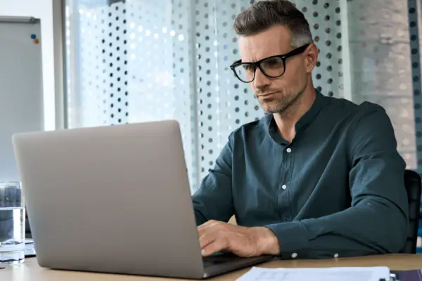 Professional man researching is it worth suing someone for a car accident on laptop in modern office