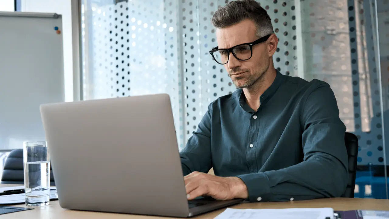 Professional man researching is it worth suing someone for a car accident on laptop in modern office