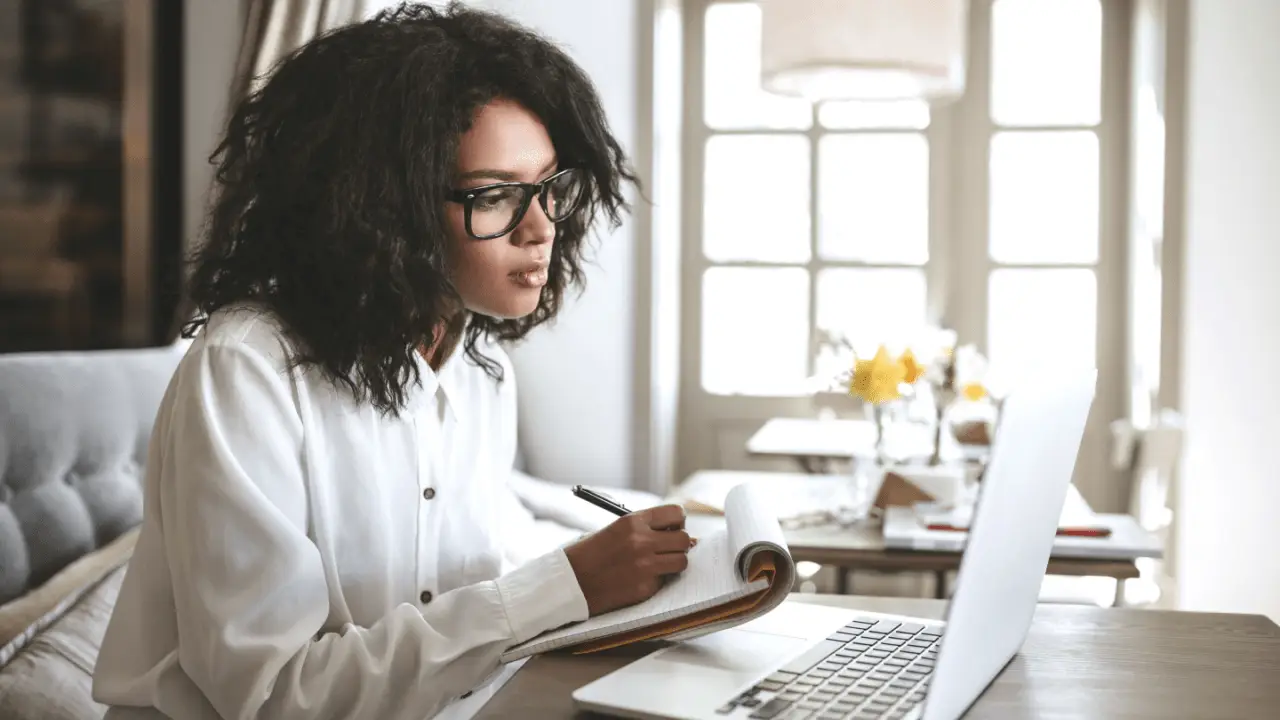 Professional woman researching qualities of the best car accident lawyer while taking notes at laptop in bright home office