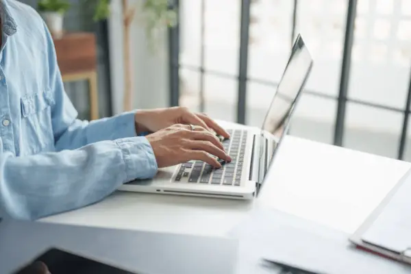Woman researching what is a good settlement offer for a car accident while typing on laptop at bright office desk