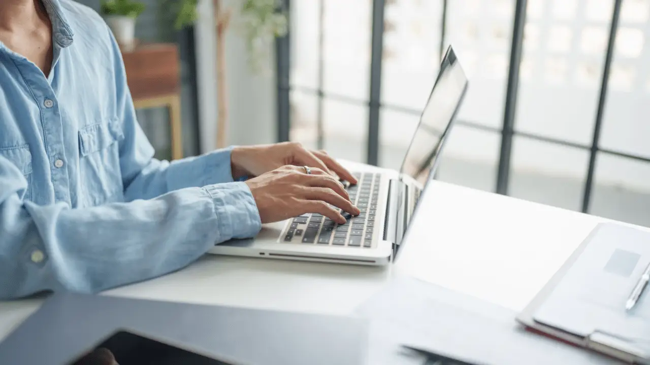 Woman researching what is a good settlement offer for a car accident while typing on laptop at bright office desk