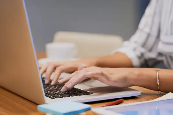 Woman researching what is a pain and suffering calculator while typing on laptop at home office desk