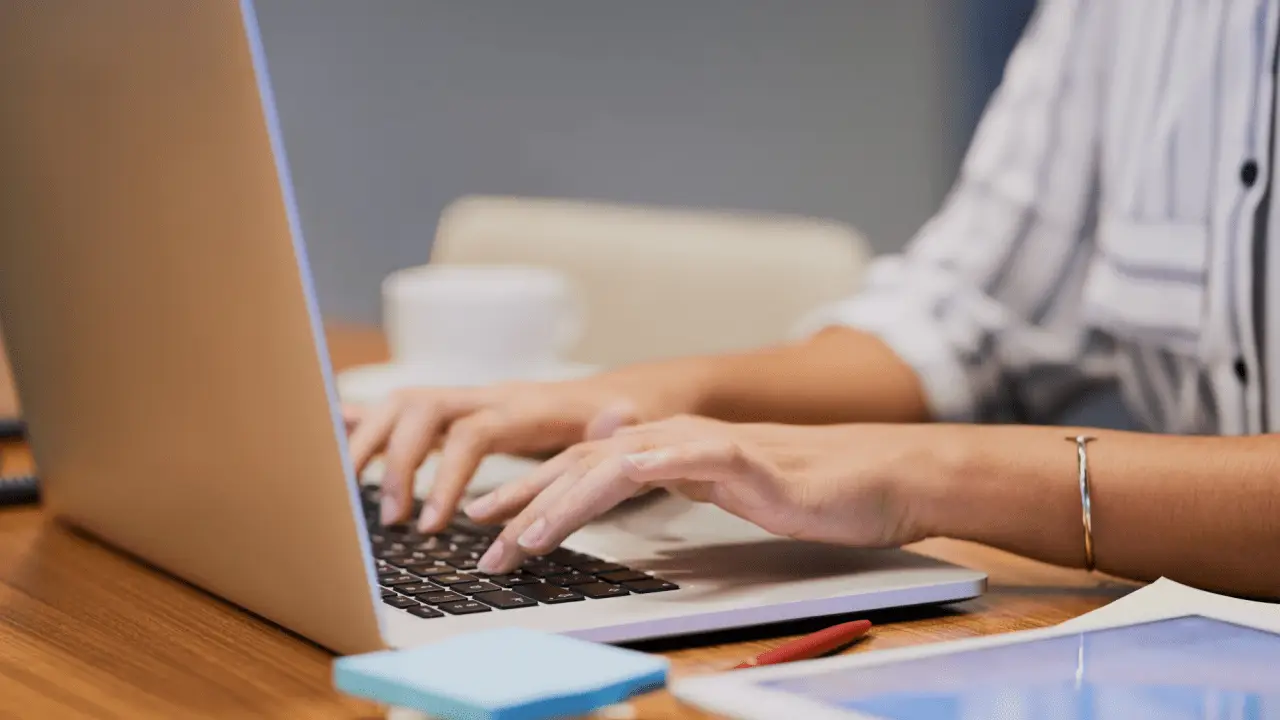 Woman researching what is a pain and suffering calculator while typing on laptop at home office desk