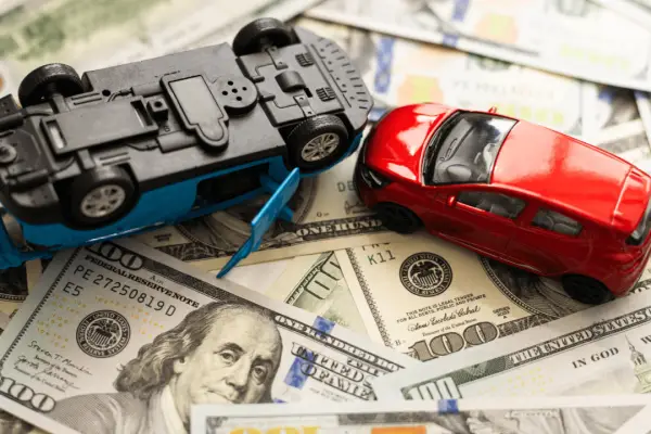 Car accident lawsuit money damages with toy cars and cash representing what is the maximum you can sue for a car accident