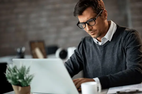 Professional man researching what percentage do accident attorneys take while working on laptop in modern office setting