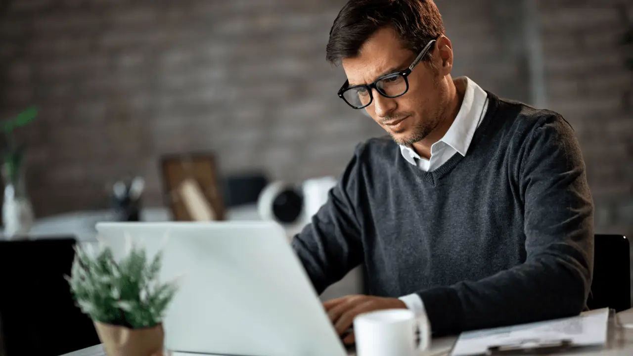 Professional man researching what percentage do accident attorneys take while working on laptop in modern office setting