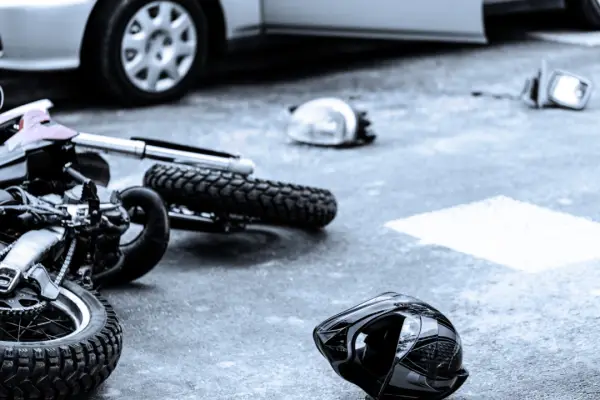 Motorcycle accident scene showing fallen bike and helmet to illustrate are motorcycle accidents covered by insurance article