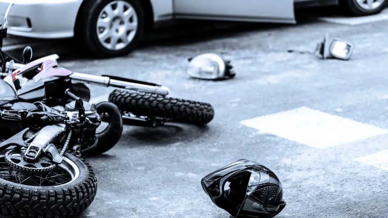 Motorcycle accident scene showing fallen bike and helmet to illustrate are motorcycle accidents covered by insurance article