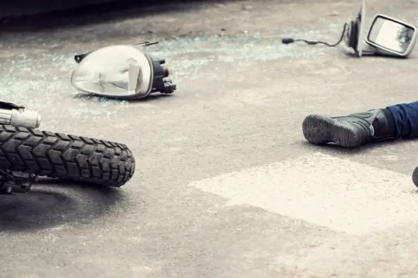 Motorcycle accident scene showing broken parts and rider on ground illustrating how many days to recover from a motorcycle accident