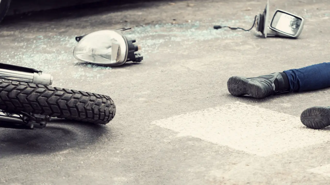 Motorcycle accident scene showing broken parts and rider on ground illustrating how many days to recover from a motorcycle accident