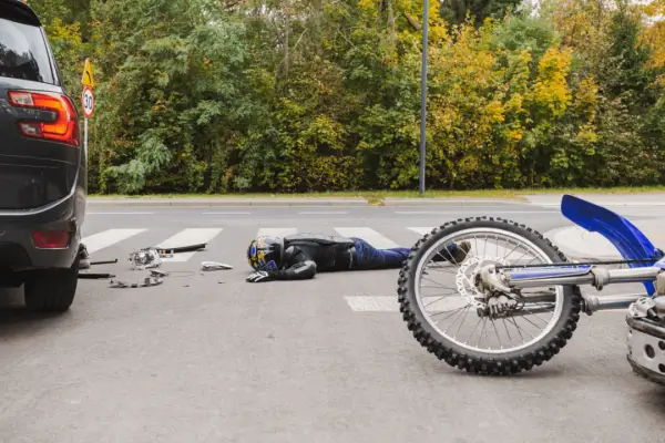 Totaled motorcycle accident scene showing damaged blue bike and rider after collision, illustrating how much will insurance pay for my totaled motorcycle