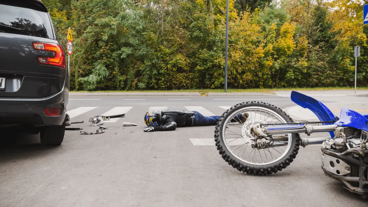 Totaled motorcycle accident scene showing damaged blue bike and rider after collision, illustrating how much will insurance pay for my totaled motorcycle