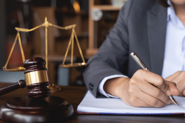 Injury lawyer writing case notes with gavel and scales showing the role of injury lawyers in motorcycle cases