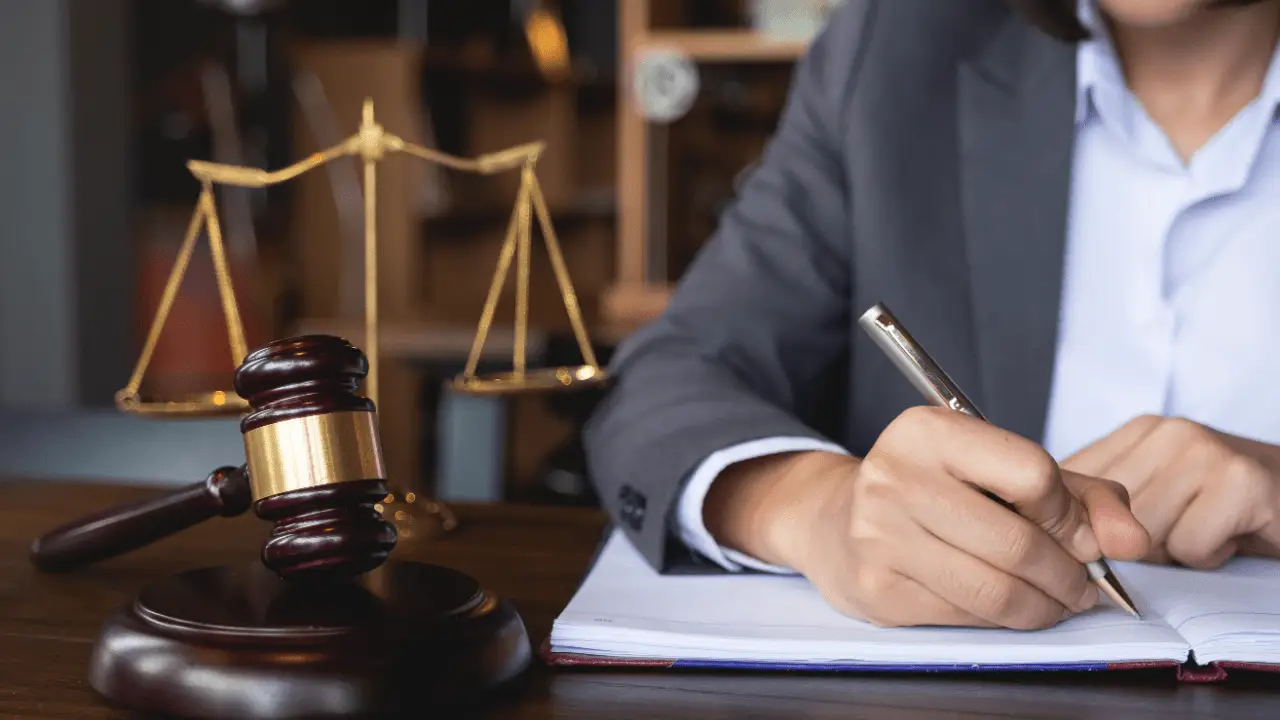 Injury lawyer writing case notes with gavel and scales showing the role of injury lawyers in motorcycle cases