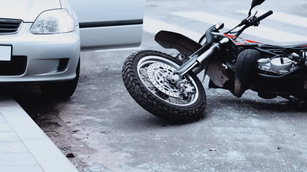 Motorcycle accident scene showing what percentage of motorcycle accidents are at fault - fallen bike and car collision on road