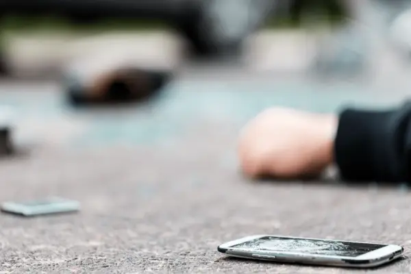 Motorcycle accident scene showing when should i call a motorcycle accident lawyer with damaged phone on pavement
