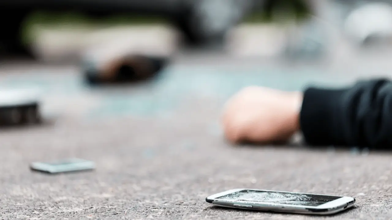 Motorcycle accident scene showing when should i call a motorcycle accident lawyer with damaged phone on pavement