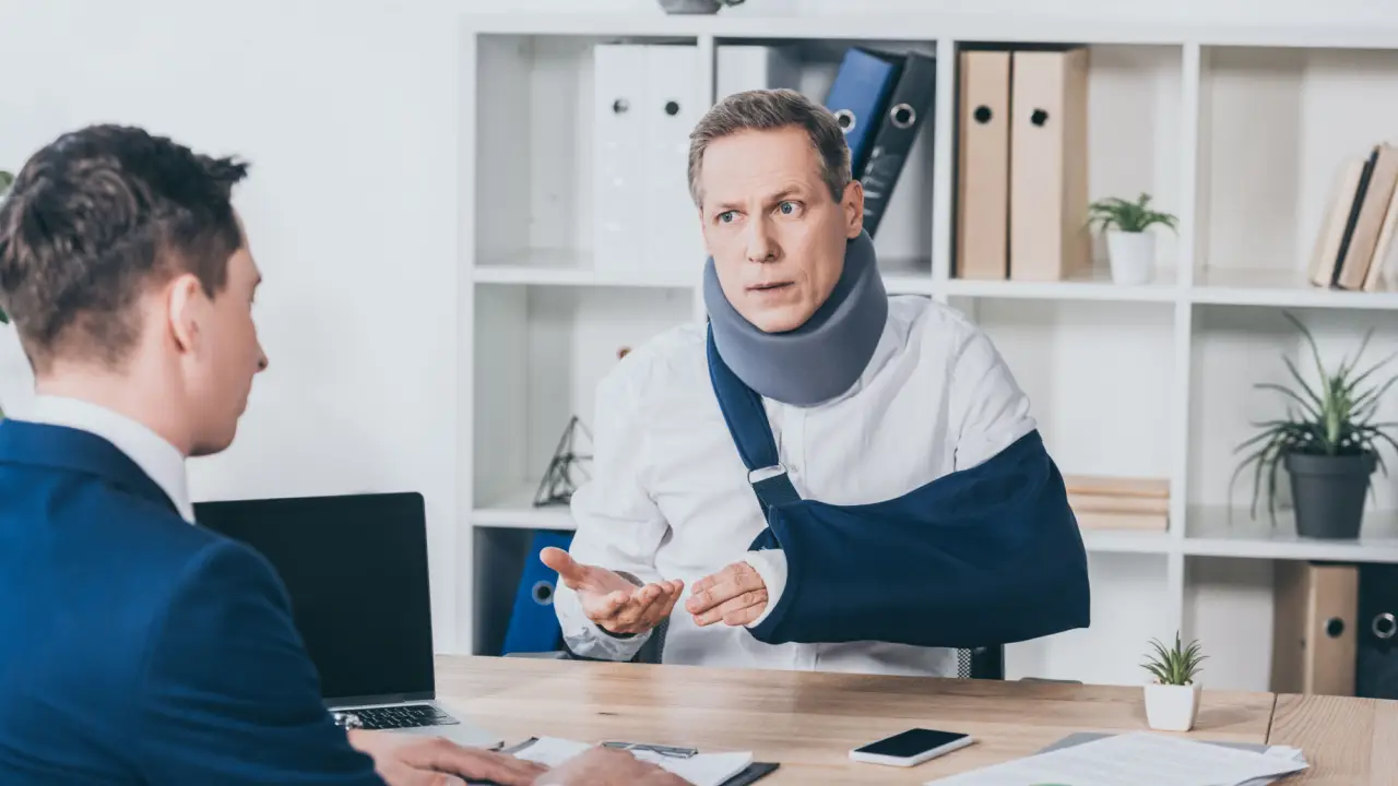 Injured man with neck brace and arm sling consulting lawyer about what injuries pay the most compensation