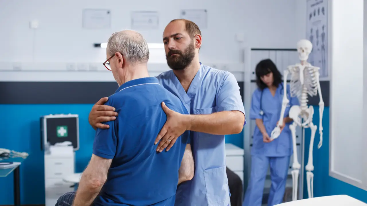 Doctor examining elderly patient's back pain after car accident to determine compensation-worthy injuries