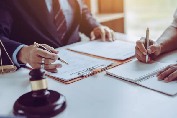 Legal consultation about pain and suffering in car accident claims with lawyer and client reviewing documents at law office desk with gavel and scales of justice