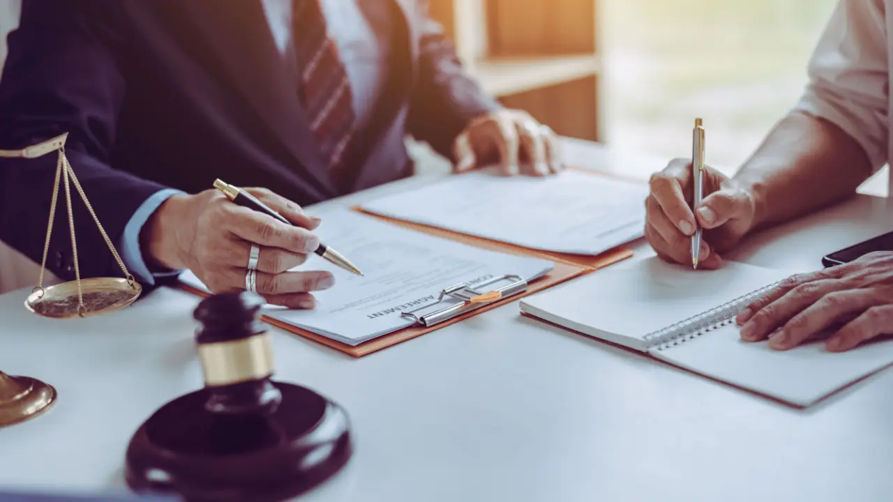 Legal consultation about pain and suffering in car accident claims with lawyer and client reviewing documents at law office desk with gavel and scales of justice