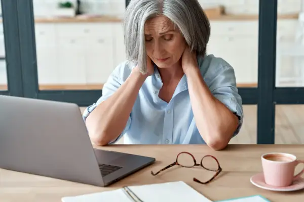 Woman with neck pain at computer learning how do I document my pain and suffering after injury