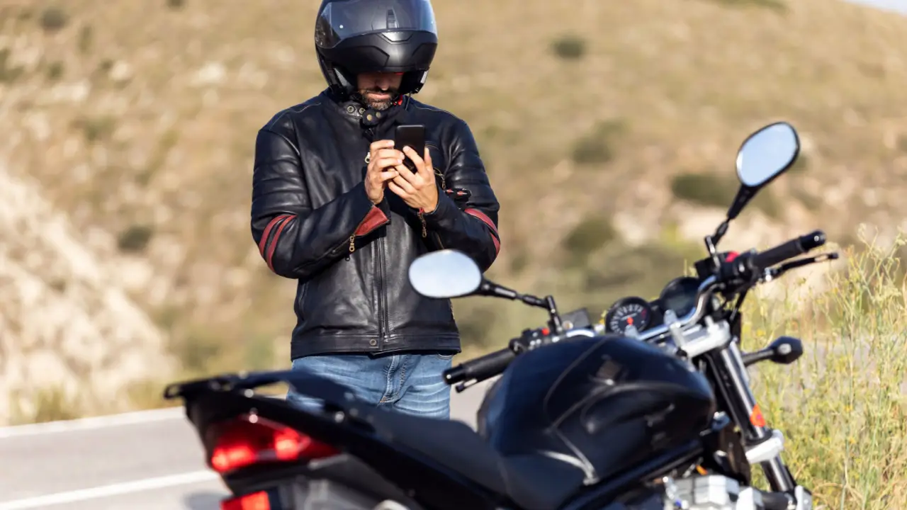 Motorcyclist checking phone after accident learning how to choose a lawyer after motorcycle accident