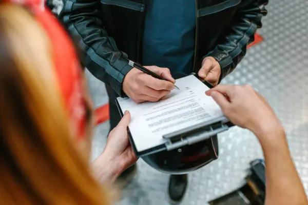 Motorcyclist signing legal documents with attorney after crash showing how to hire the best motorcycle accident lawyer