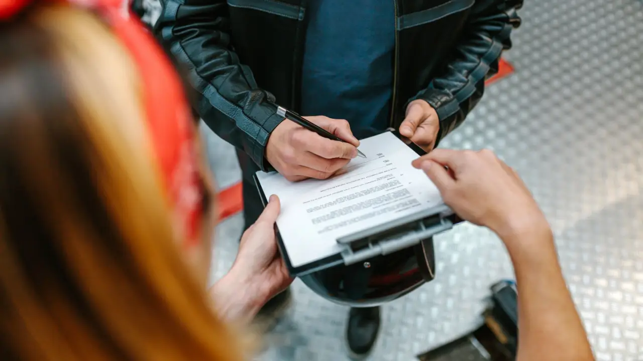 Motorcyclist signing legal documents with attorney after crash showing how to hire the best motorcycle accident lawyer