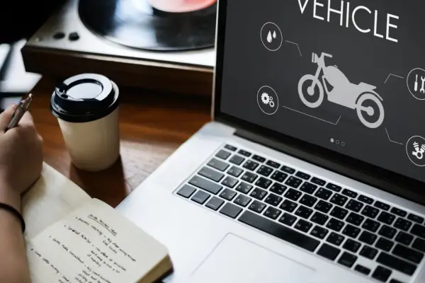 Person researching how can a motorcycle accident lawyer help on laptop with motorcycle vehicle diagram and coffee