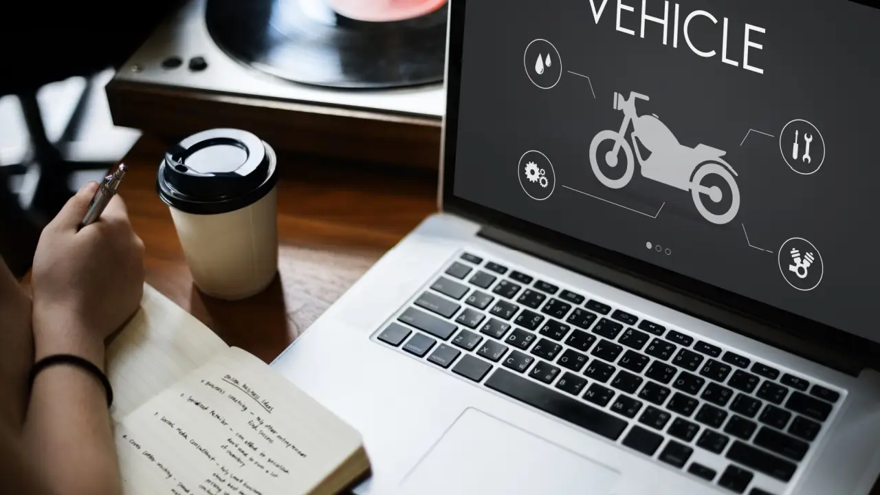 Person researching how can a motorcycle accident lawyer help on laptop with motorcycle vehicle diagram and coffee