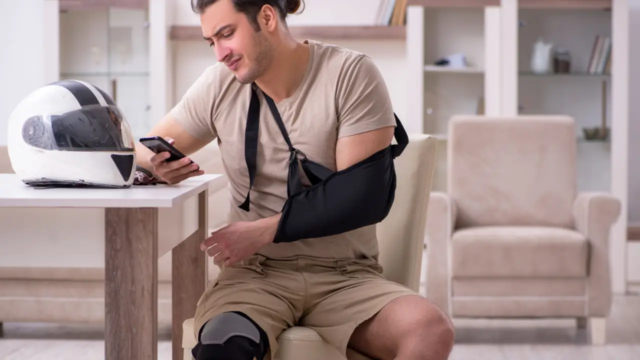 Injured motorcyclist with arm sling and leg brace at home considering how much are most motorcycle accident settlements worth