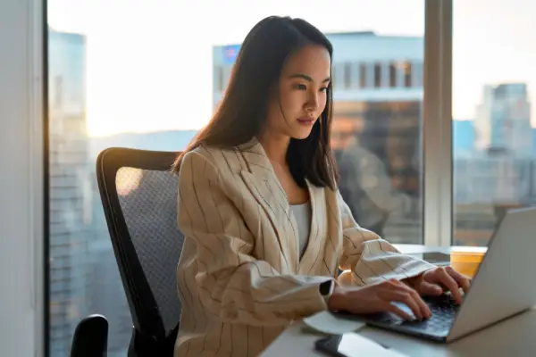 Professional woman researching how often do personal injury lawyers win using laptop in modern office with city skyline view