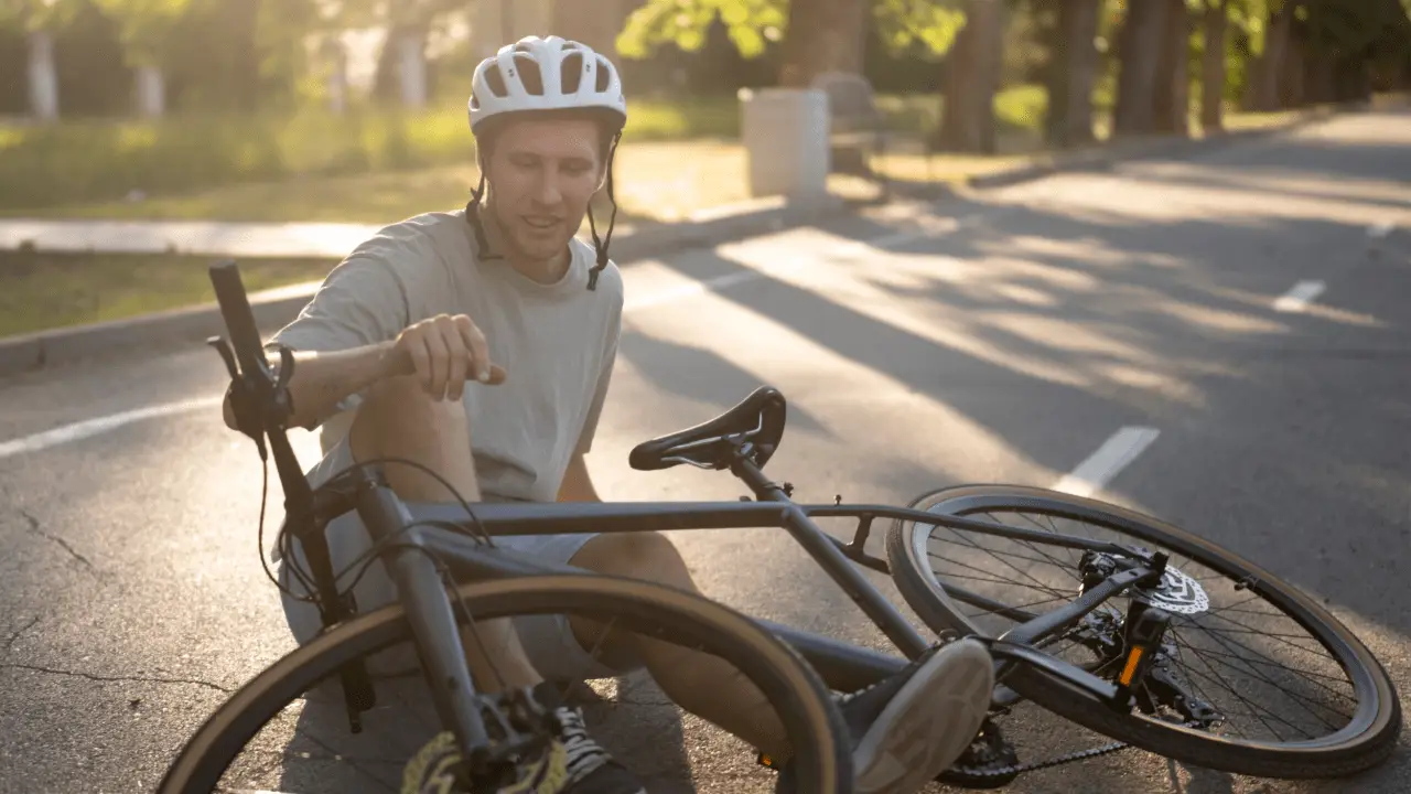 Injured cyclist holding arm on road after crash showing concerns about after a Florida bicycle accident who pays my medical bills