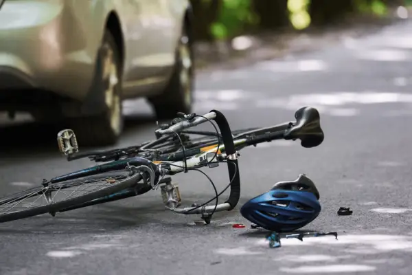 Bicycle accident scene with fallen bike and helmet near car showing does car insurance cover bicycle accident situations on road