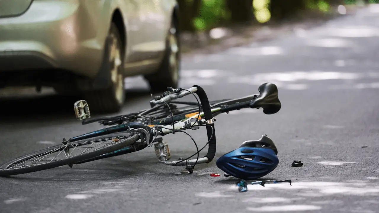 Bicycle accident scene with fallen bike and helmet near car showing does car insurance cover bicycle accident situations on road