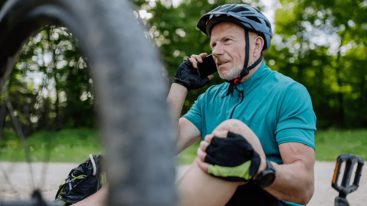Cyclist wearing protective bicycle helmet making emergency phone call demonstrating how do bicycle helmets protect the head in an accident
