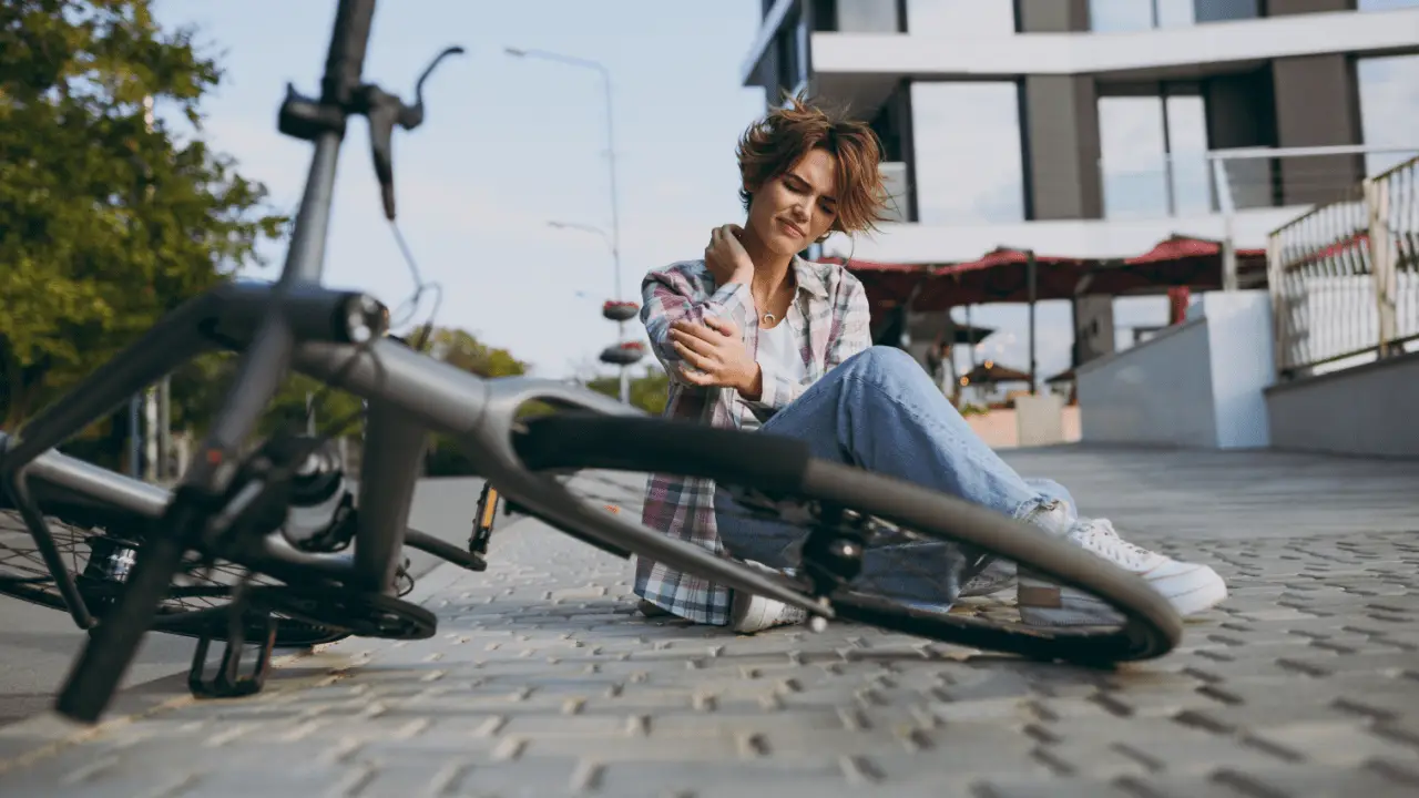 Injured woman cyclist holding shoulder after bike accident demonstrating how to claim for bicycle accident in urban area