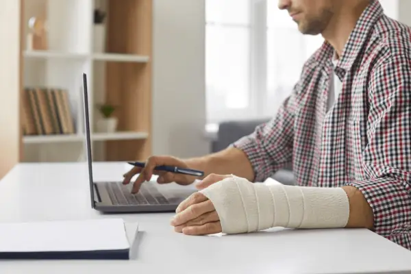 Injured cyclist with bandaged arm using laptop researching how to find a lawyer after a bicycle accident
