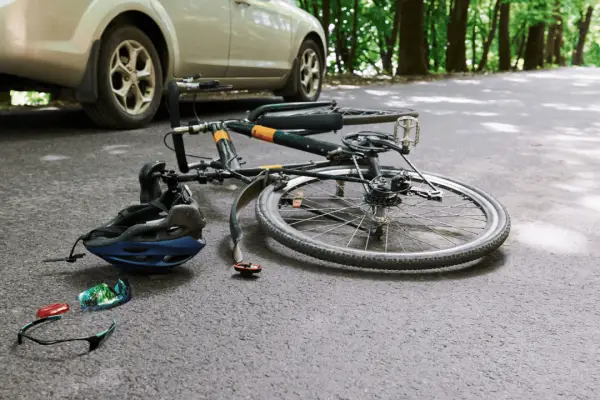 Bicycle accident scene on road showing what percent of bike riders get into accidents with fallen bike helmet and car nearby