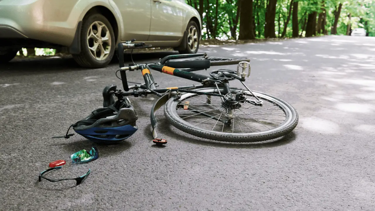 Bicycle accident scene on road showing what percent of bike riders get into accidents with fallen bike helmet and car nearby