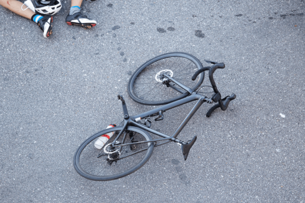 Overhead view of fallen road bike on pavement showing what type of bike has the most accidents with injured cyclist nearby