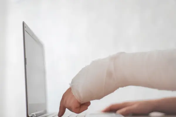 Injured cyclist with bandaged arm using laptop researching what to do after a hit and run bicycle accident