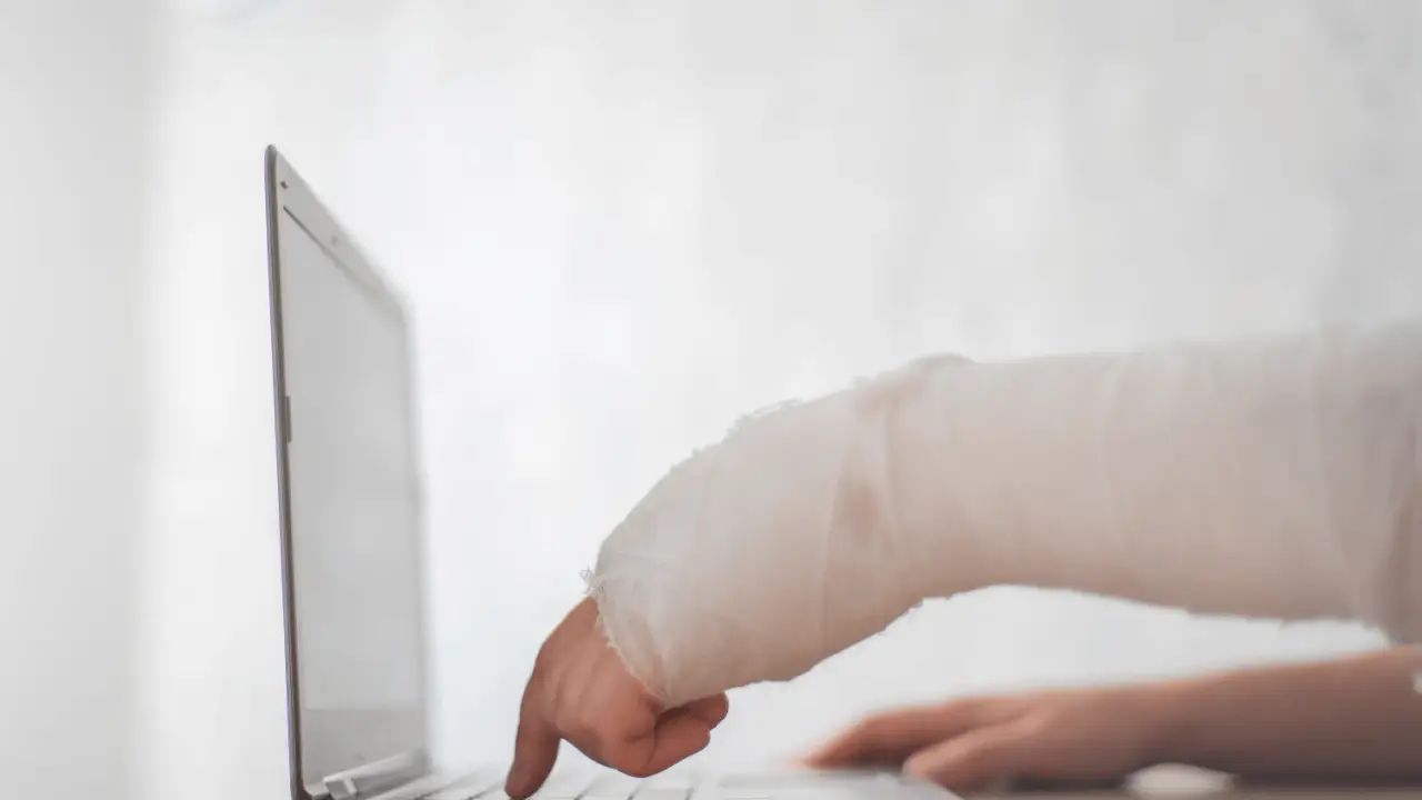 Injured cyclist with bandaged arm using laptop researching what to do after a hit and run bicycle accident