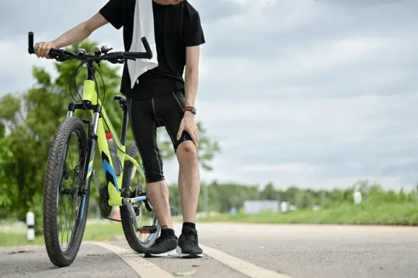 Injured cyclist standing on roadside with knee wound showing where do most bicycle fatalities happen on public roads