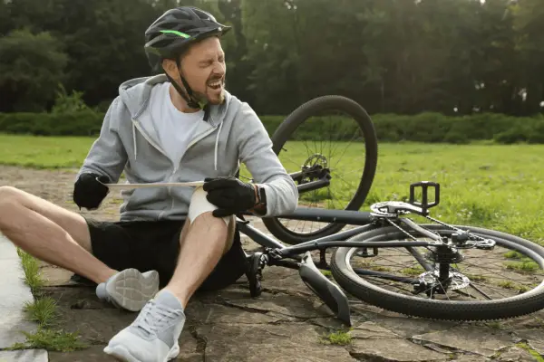 Injured cyclist in pain holding leg after bike crash illustrating why do i need a bicycle accident lawyer for legal protection