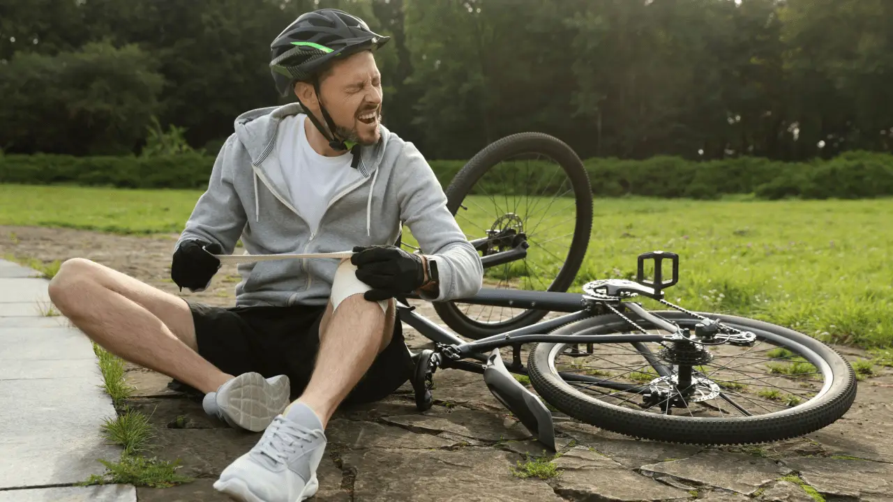 Injured cyclist in pain holding leg after bike crash illustrating why do i need a bicycle accident lawyer for legal protection