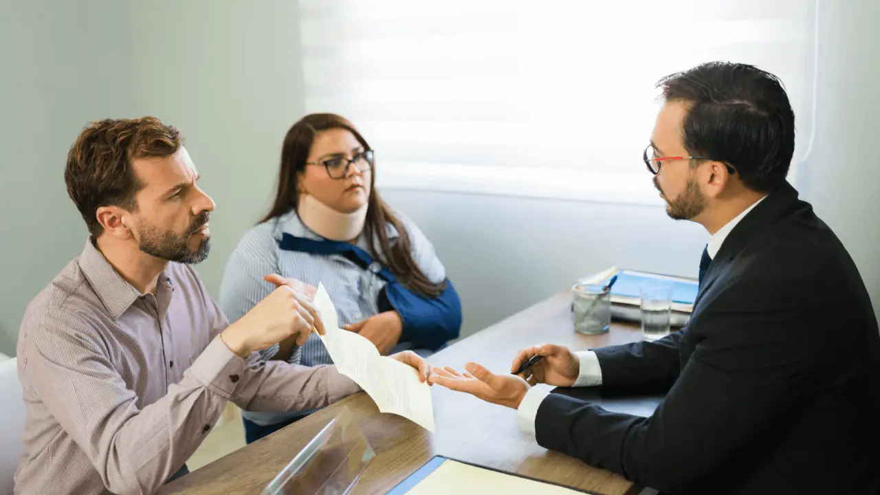 Couple meeting with attorney reviewing settlement documents to understand how are personal injury settlements calculated