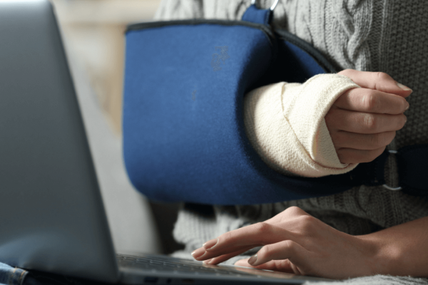 Injured person with cast researching how to choose a personal injury lawyer on laptop
