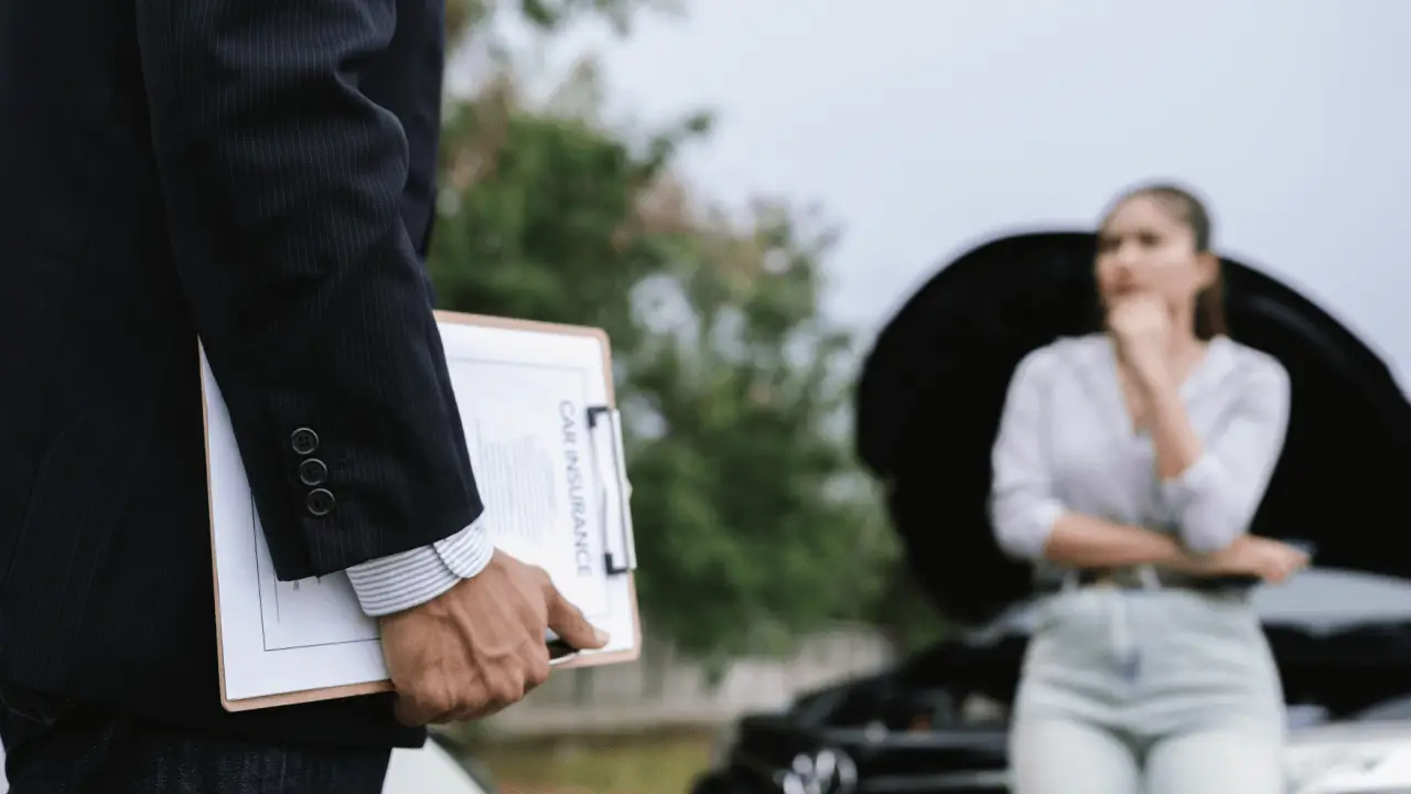 Insurance claim not at fault adjuster holding car insurance clipboard with concerned woman standing near damaged vehicle
